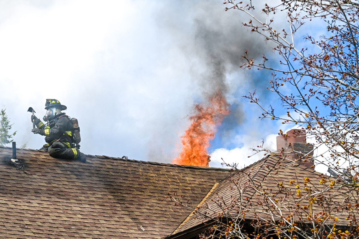 A Spokane firefighter vents the roof during an apartment blaze Tuesday at the corner of Eighth Avenue and Jefferson Street.  (DAN PELLE/THE SPOKESMAN-REVIEW)